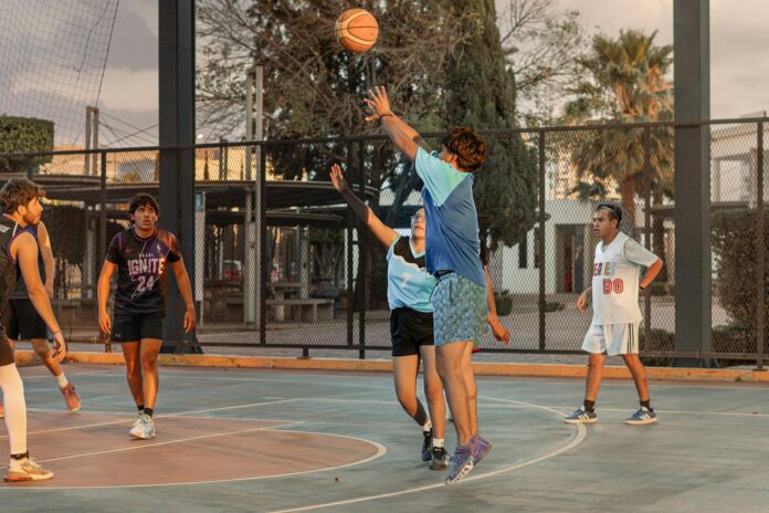High-energy outdoor basketball game with players shooting and defending on a street court.